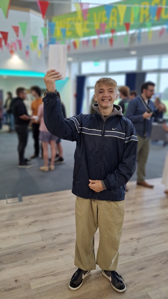 A photo of Alfie holding his results up in the air.