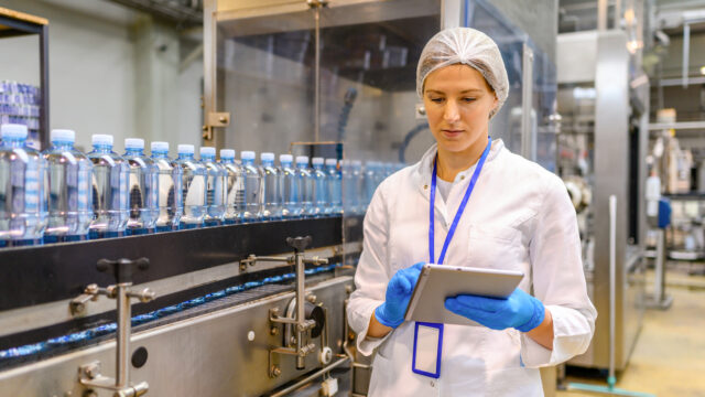 Female engineer working on maintenance in bottling plant. Inspection quality control.