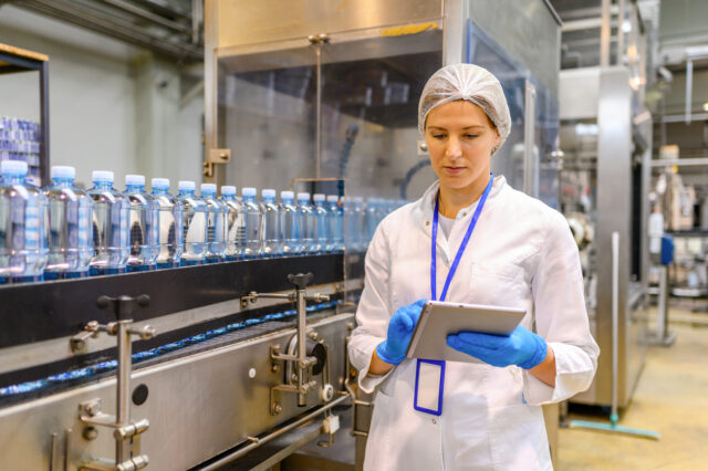 Female engineer working on maintenance in bottling plant. Inspection quality control.