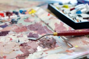 A close-up of paint on a palette with a palette knife.