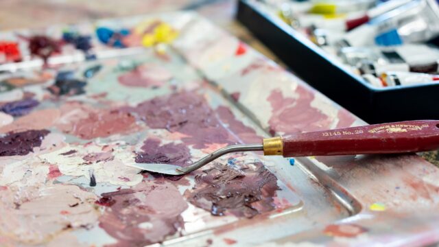 A close-up of paint on a palette with a palette knife.