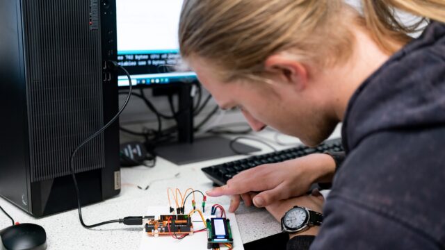A student looking at a small electrical circuit.