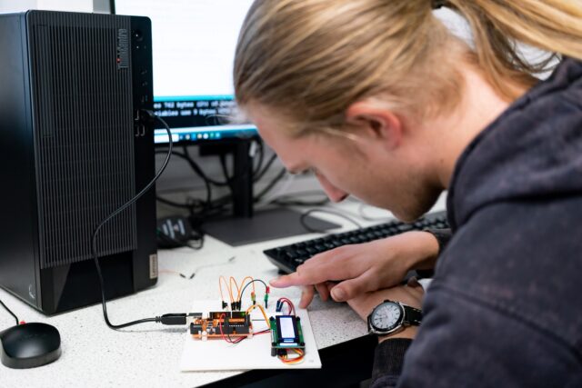 A student looking at a small electrical circuit.