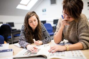 Two people looking at a book together.