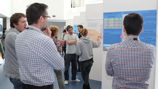 Staff stand and look at posters on walls.
