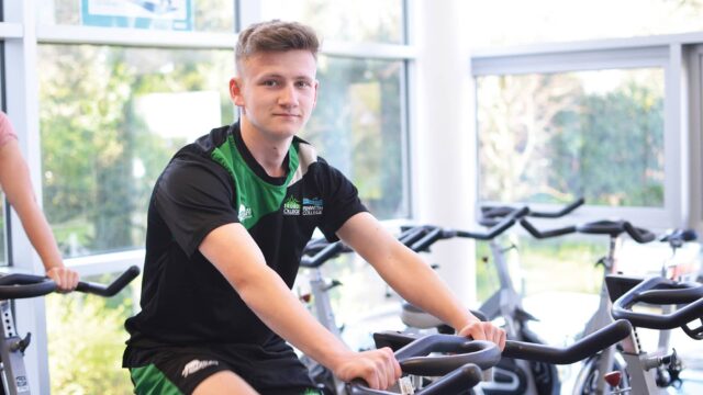 A student on an exercise bike in a college gym.
