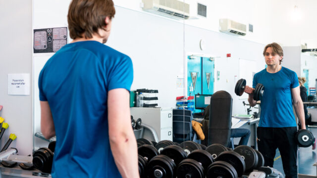A young perosn working out in the college gym.