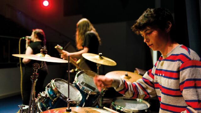 A student band where the focus is on the drummer.