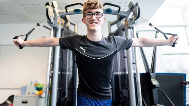 A student using weight lifting machines at the college's gym.
