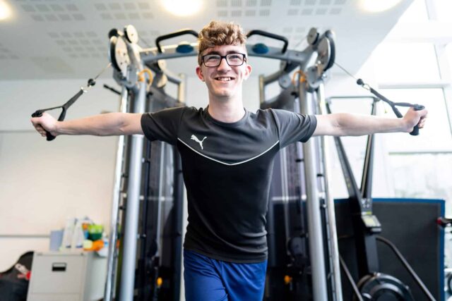 A student using weight lifting machines at the college's gym.