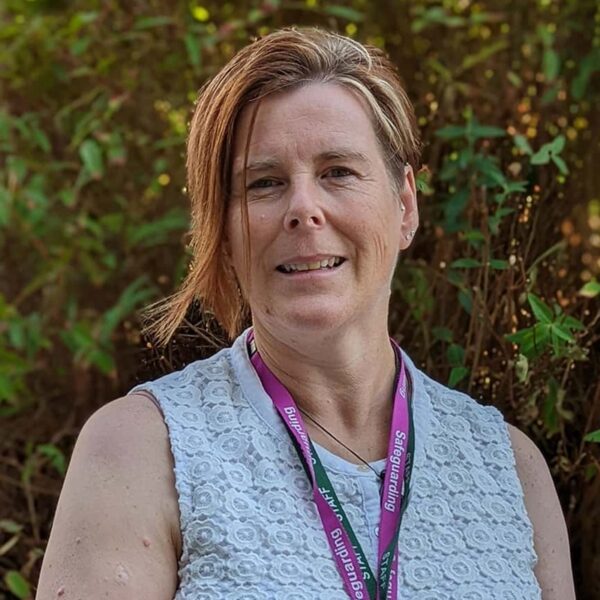 A photo of Bridget. She is wearing a white top and two staff lanyards.