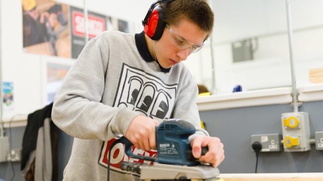 A student using an electric sander.