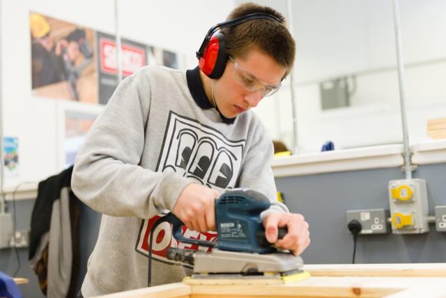 A student using an electric sander.