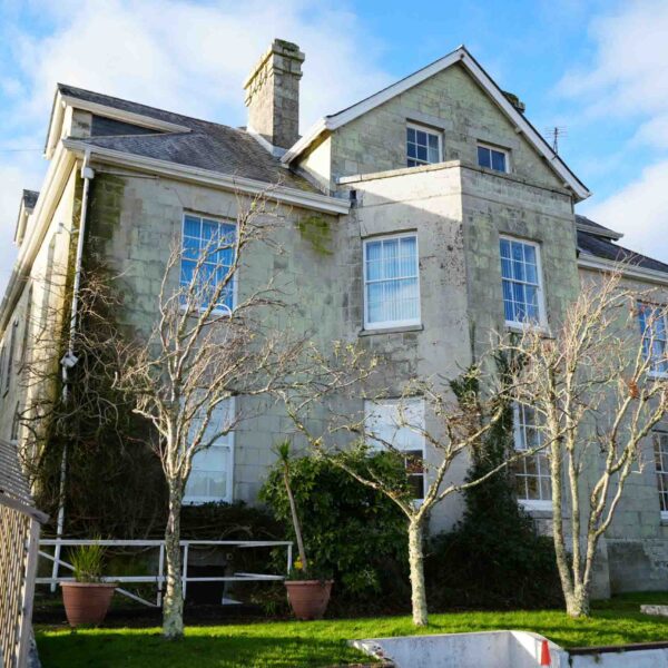 A picture of the exterior of Tregye house. The trees are bare signifying winter and the sky is blue.