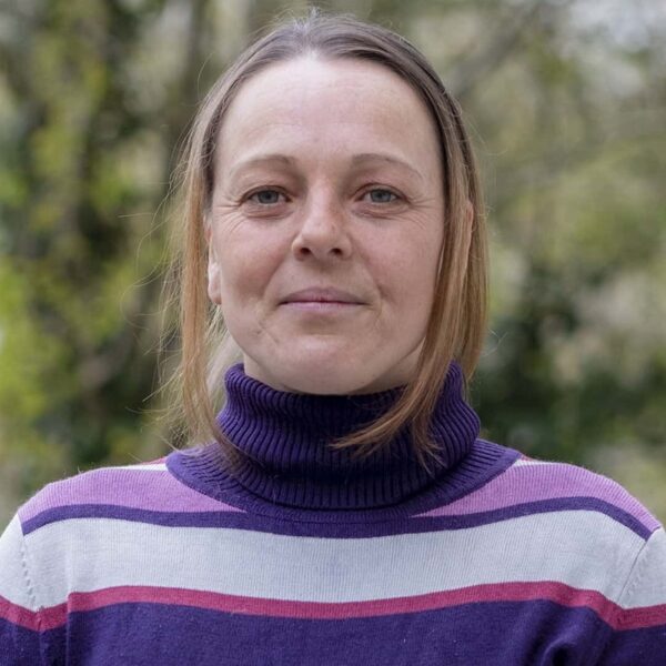 A photo of Ceri. She is wearing a purple and pink striped top.