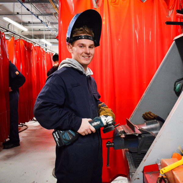 A student is wearing overalls and a welding mask.