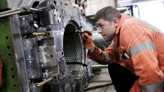 An engineer shines a torch into a metal drum.