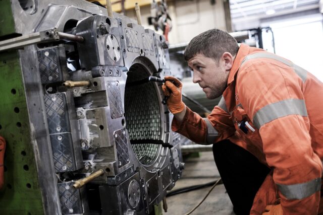 An engineer shines a torch into a metal drum.