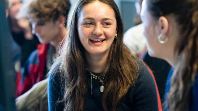 A student sat opposite another student smiling.