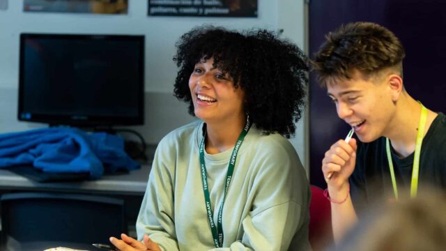 Two students sat side by side smiling.