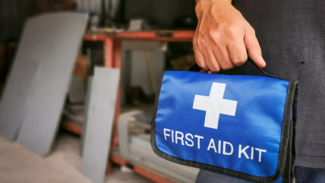 Worker holding first aid kit bag in the factory.