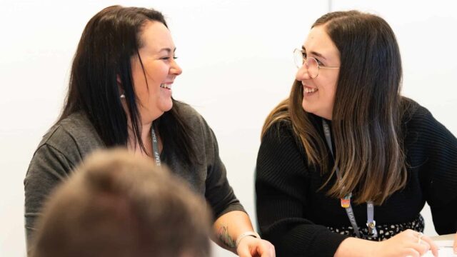Two members of staff smile and laugh at each other.