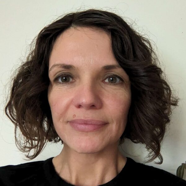 A photo of Gosia, she is in a black top and is stood against a plain white background.