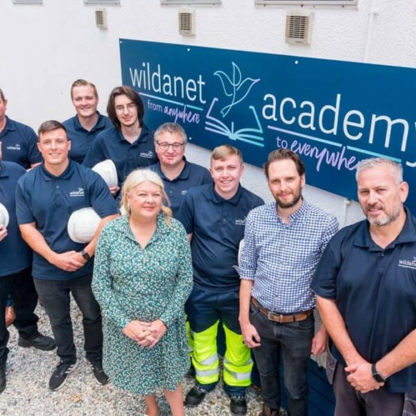Workers from Wildanet stand outside in their uniforms. A sign that says Wildanet behind them.