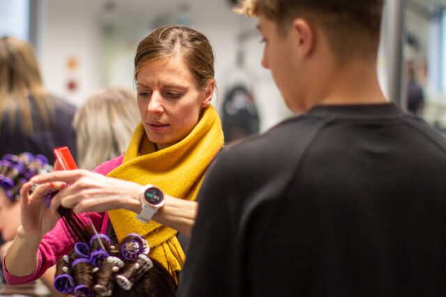 A tutor putting rollers in a client's hair.