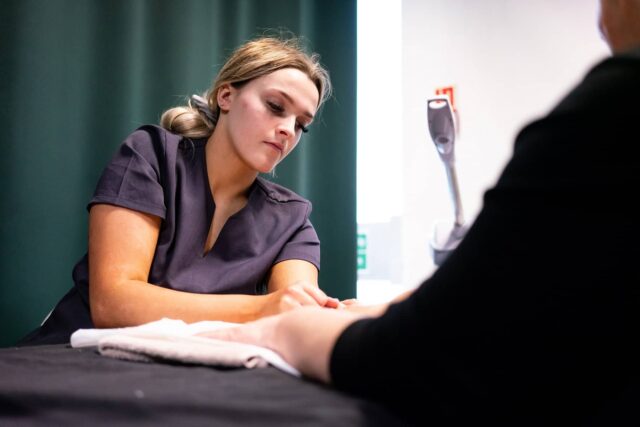 A hair and beauty student doing a hand treatment on a client.