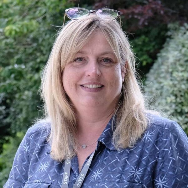A photo of Hannah Hopkins smiling. She is wearing a blue shirt and her staff lanyard.