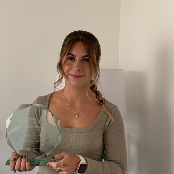 A photo of Amber holding a glass trophy. She is smiling at the camera.
