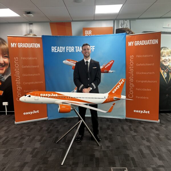 Joshua stands behind a model aeroplane of an EasyJet aircraft.