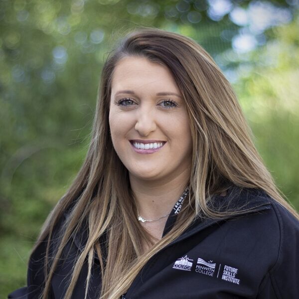 A photo of Jenna smiling. She is wearing a black college branded top.