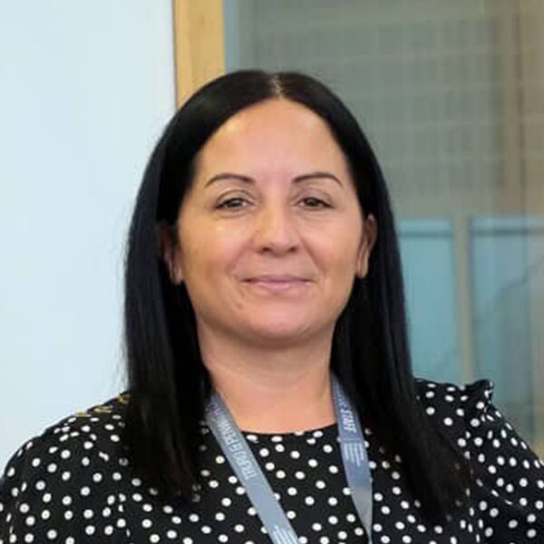 A photo of Jolene, she is wearing a black dress with white polka dots and a staff lanyard.