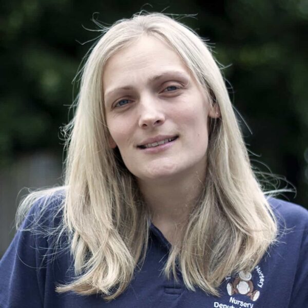 A photo of Kerry. She is wearing a blue polo shirt with the nursery logo on it.