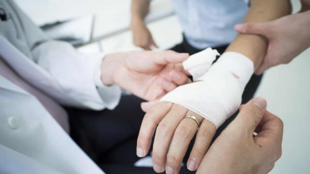A nurse wraps a person's hand in a bandage.