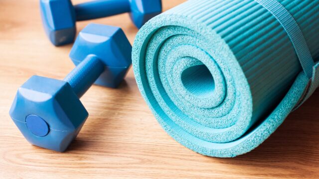 A blue yoga mat and two dumbbells.