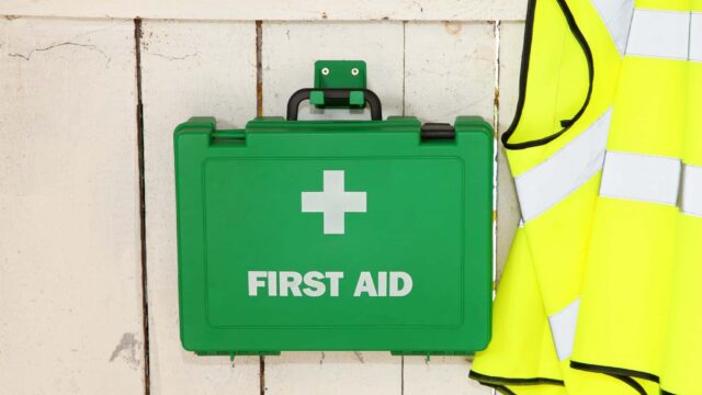 A first aid box hanging on the wall with a high-vis jacket.