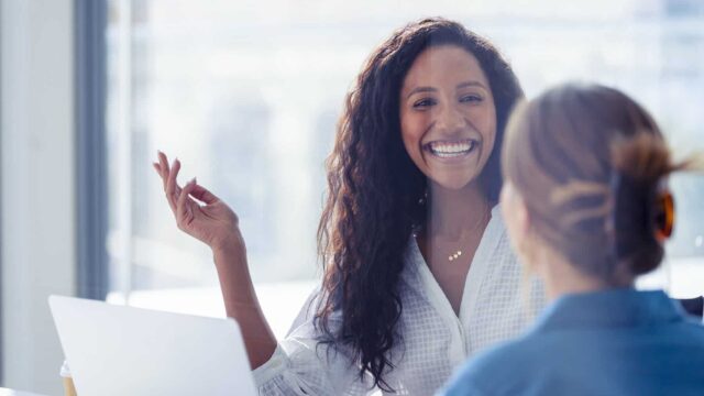 Two women look at each other and smile.