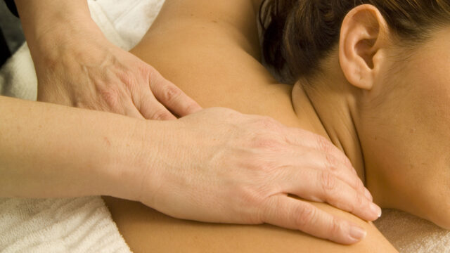 Close up of hands on a person's shoulders.