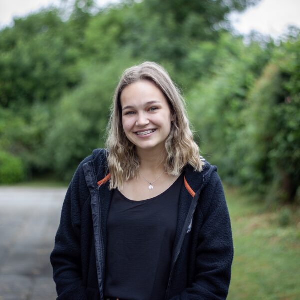 Millie stands outside wearing a fleece with her hands in her pockets.