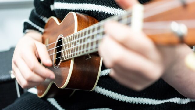 Close up of hands playing a ukulele.