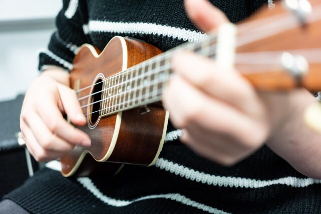 Close up of hands playing a ukulele.