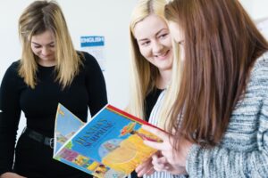 Three students look through a childern's book together.