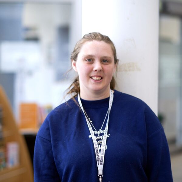 Natasha is stood in the Fal building with a pillar behind her.