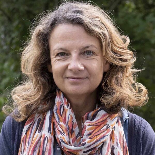 A photo of Nicky. She is wearing a blue top and a colourful scarf.
