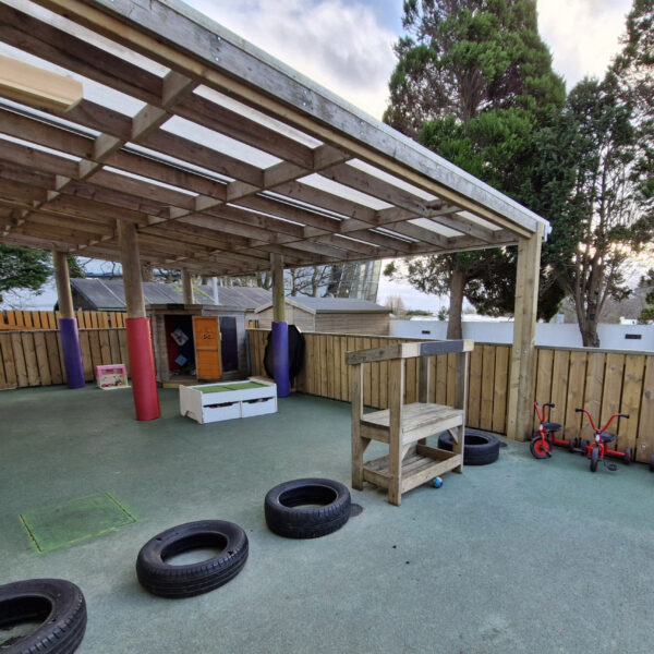 An image of the play area at Truro College's Nursery. There are little red trikes and there are empty tires.