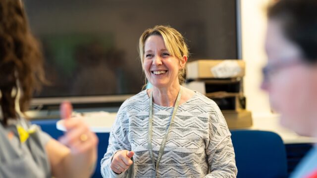 A tutor smiles happily at an unrecognisable person.