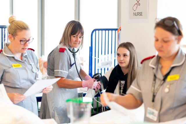 A nursing student is monitoring the blood pressure of a young woman in the health simulation suite at the University Centre.